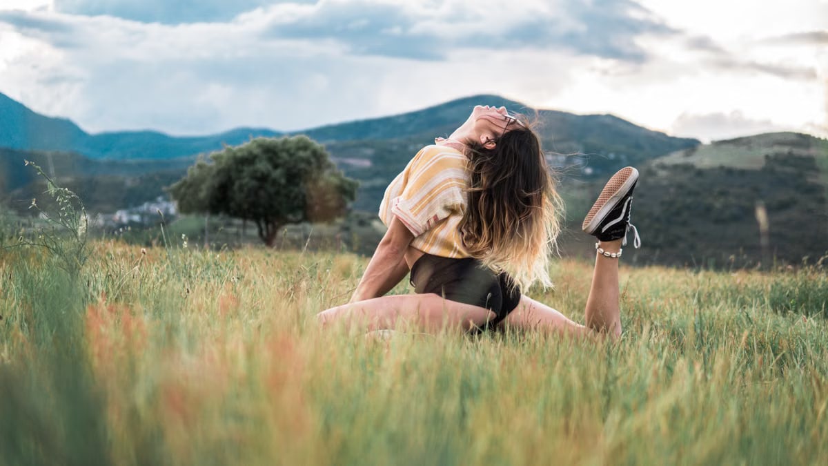 A young woman posing elegantly in a scenic countryside setting, enjoying nature and freedom.